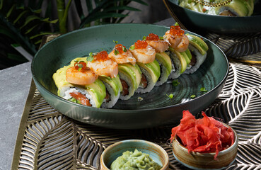 Sushi and rolls on a gray dish with Chinese chopsticks, wasabi and sauce.