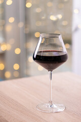 A glass of red wine on a beige light wooden table in a restaurant