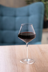 A glass of red wine on a beige light wooden table in a restaurant