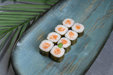 Multicolored sushi and rolls in a gray dish in a restaurant.
