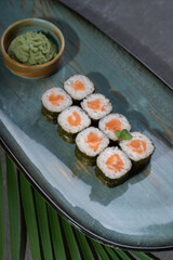 Sushi and rolls on a gray dish with Chinese chopsticks, wasabi and sauce.