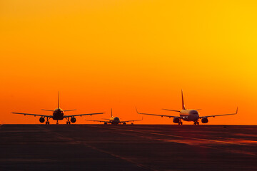 Fototapeta na wymiar Landing airplanes against colorful sky at sunset. Travel background with passenger plane. Evacuation