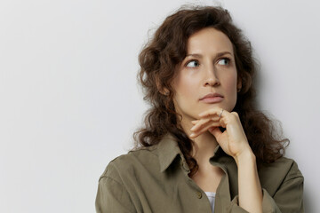 Fototapeta na wymiar Thoughtful pensive serious unhappy curly beautiful woman in casual khaki green shirt recline on hand looks aside posing isolated on over white background. People Emotions Lifestyle concept. Copy space