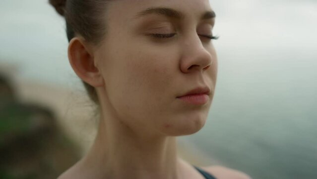 Closed eyed girl meditating on beach close up. Woman breathing practicing yoga.