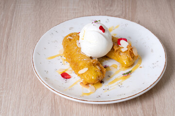 Fried bananas with scoops of ice cream on a white plate