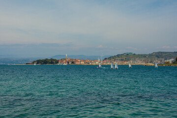 Fototapeta premium The historic town of Izola on the Adriatic coast of Slovenia. A sailing school practices in the foreground right 