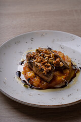 A dish of nuts, duck liver and sauce on a white plate