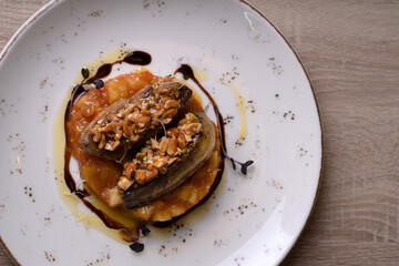 A dish of nuts, duck liver and sauce on a white plate