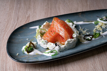 Red fish in white sauce with herbs. Dish close-up.