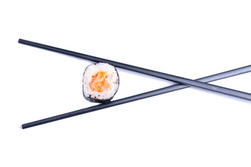 Two chopsticks holding fresh sushi roll isolated on white background