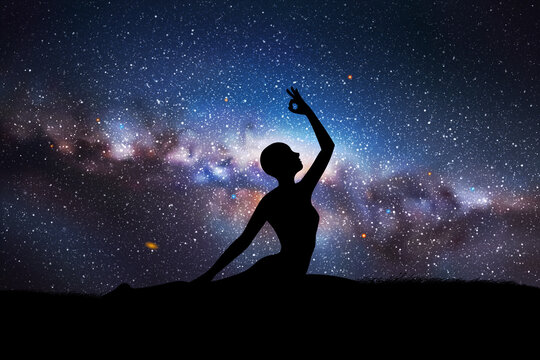 Yogi girl silhouette on grass. Woman doing yoga at night. Milky Way