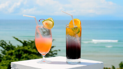 Two tropical fresh iced mocktails on the bar table with sea beach on background. Cocktails on luxury tropical vacation. Thailand Asia summer travel