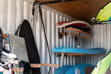 Interior of windsurf boards storage room in old rusty metal shipping container box with racks on...