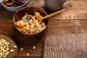 A plate of couscous with saffron and nuts on a wooden table next to dates and nuts. save a place.