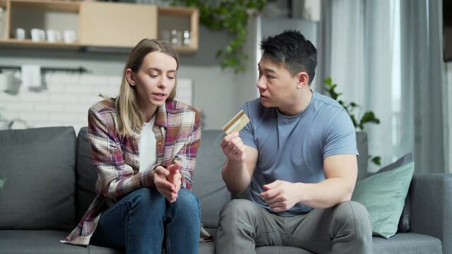 domestic violence woman quarreling with husband. Nervous asian man sitting on the couch in foreground while his wife shouting at him. couple problems and conflict in young family at home