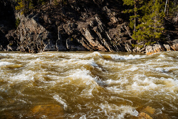 A powerful threshold on a mountain river, the water is bubbling in the channel, the steep rock...