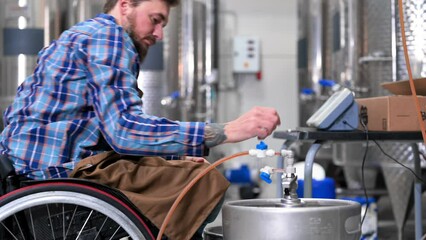 Person with disability who uses a wheelchair working at craft beer factory. High quality 4k footage - Powered by Adobe