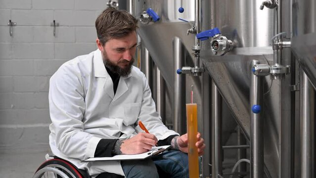 Professional brewmaster controlling craft beer production process in brewery, measuring beverage density with hydrometer. High quality 4k footage