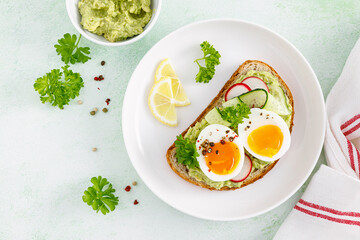 Toast with boiled egg, radish, cucumber and avocado pate. Top view