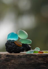 Different colours of sea glass pebbles balances on a lava stone