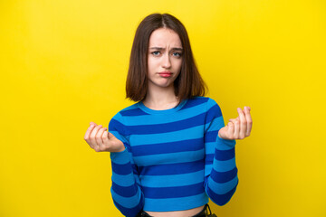 Young Ukrainian woman isolated on yellow background making money gesture but is ruined