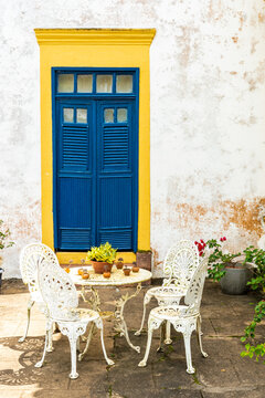 White table and chairs in front of colorful doorstep of old traditional house in Brazil
