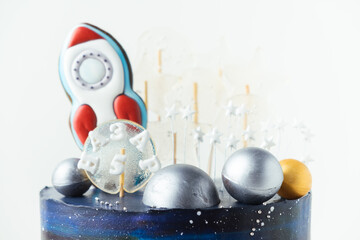 Space themed birthday cake with blue cream cheese frosting decorated with gingerbread cookies in...