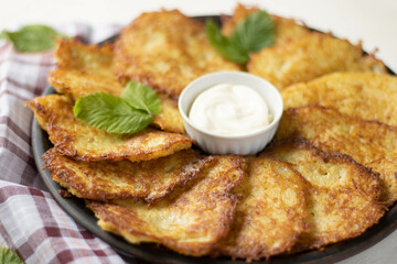 Potato pancakes with garlic and bacon, sour cream on wooden table
