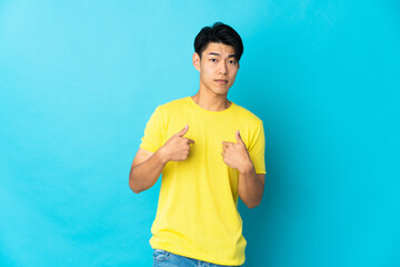 Young Chinese man isolated on blue background pointing to oneself