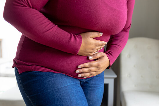 Midsection of african american mid adult woman with hands on stomach suffering from stomachache
