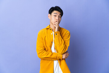 Young Chinese man isolated on purple background surprised and shocked while looking right