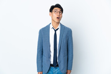 Young Chinese business man isolated on white background looking up and with surprised expression
