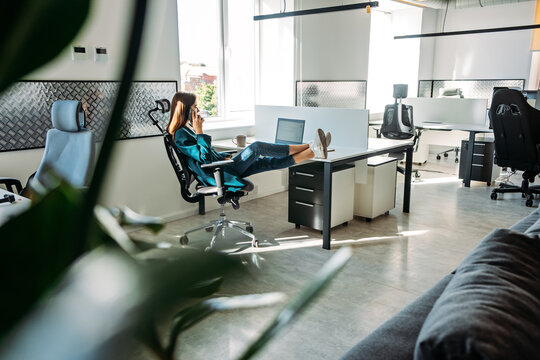 Mental Health In The Workplace. Businesswoman Woman Talking On The Phone And Relaxing At The Workplace With Her Feet On The Desktop