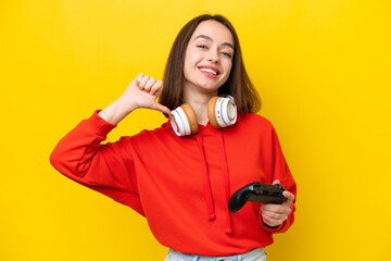 Young Ukrainian woman playing with a video game controller isolated on yellow background proud and self-satisfied