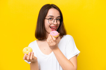 Young Ukrainian woman isolated on yellow background holding a donut