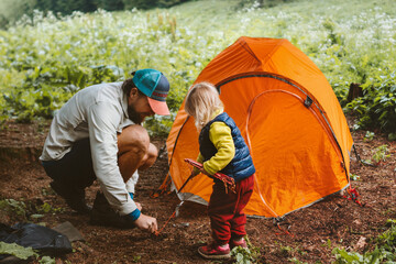 Camping family vacations child helps father to set tent travel lifestyle hiking gear tourism...