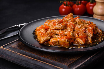 Teriyaki chicken with sauce, sesame, herbs and spices on a dark background