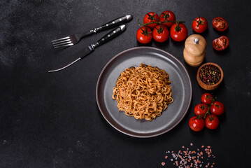 Buckwheat flour noodles with sauce, sesame, herbs and spices on a dark concrete background