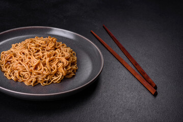 Buckwheat flour noodles with sauce, sesame, herbs and spices on a dark concrete background