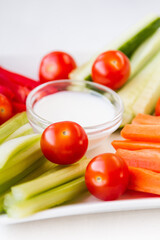 Fresh vegetables snack - carrot, celery, bell pepper, cucumber and cherry tomatoes with yogurt