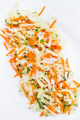 Mix salad on white plate - cabbage, carrots, cucumber