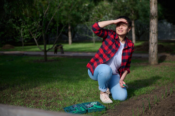 Horticulture and gardening concept. Charming female gardener covers her face from the sunlight...