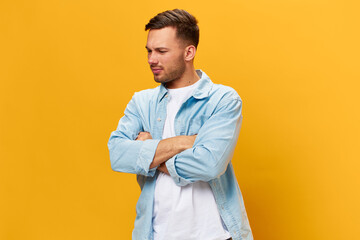 Sad frustrated tanned handsome man in blue basic t-shirt think about problem at work fold arms posing isolated on yellow studio background. Copy space Banner Mockup. People emotions Lifestyle concept