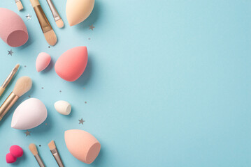 Make up concept. Top view photo of different colour beauty blenders makeup brushes and silver star shaped confetti on isolated pastel blue background with copyspace