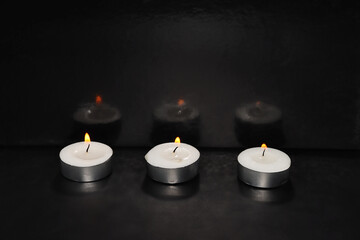 Burning candles on a black background. Photo for Holocaust Remembrance Day, Memorial Day for Fallen Soldiers and Victims of Hostile Acts,  Israel Memorial Day. In Hebrew - Yom HaShoah, Yom HaZikaron