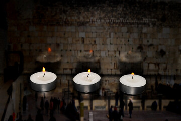 Burning candles on blurred semi transparent Jerusalem Western Wall background. Photo for Israel...