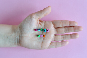 Thank you words formed with colorful letter blocks placed on a hand palm