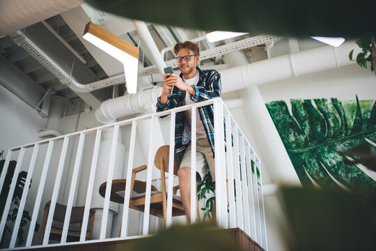 Caucasian guy use smartphone on balcony in office