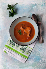 Mackerel in tomato sauce in a blue plate on a blue, pearl background