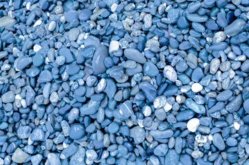Fototapeta na wymiar multi-colored pebbles on the seashore shimmers from the water in the sun free space close-up texture background